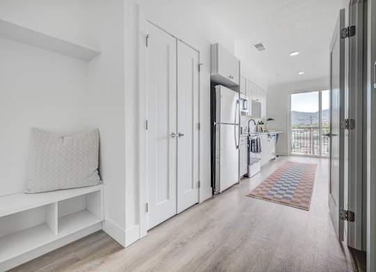 A white kitchen with a bench and a rug on the floor.