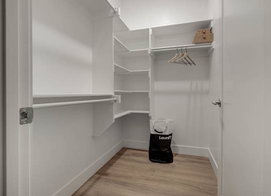 A white closet with a bag of laundry on the floor.