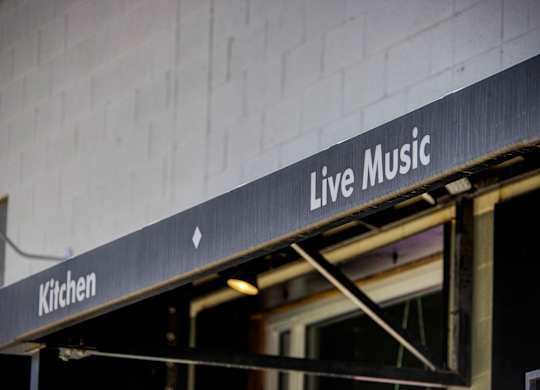 A sign that says Live Music is hanging from the side of a building.