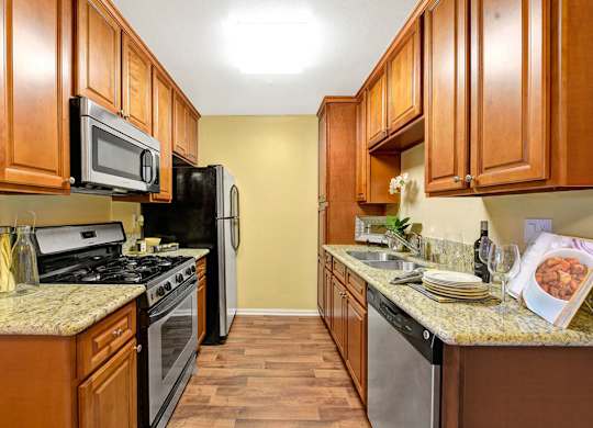 A kitchen with wooden cabinets and a granite countertop.