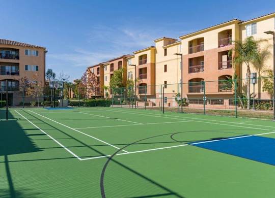 A basketball court is surrounded by apartment buildings.
