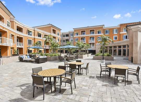 A courtyard with tables and chairs surrounded by buildings.