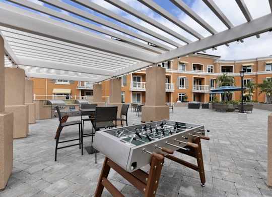 A table and chairs are set up under a white awning on a patio.