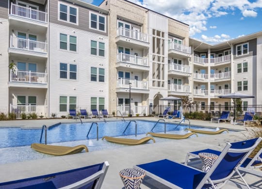 an apartment building with a swimming pool and lounge chairs