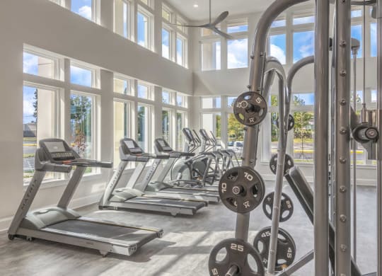 a gym with cardio equipment and windows in a building