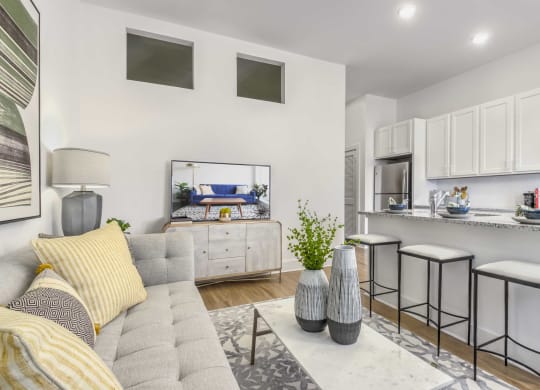 a living room with a couch and a kitchen with stools