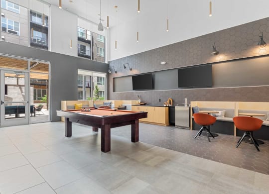 a game room with a pool table  and a kitchen