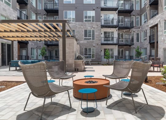 a patio with chairs and a table in front of an apartment building