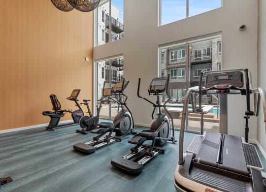 a gym with cardio equipment and a window overlooking a pool