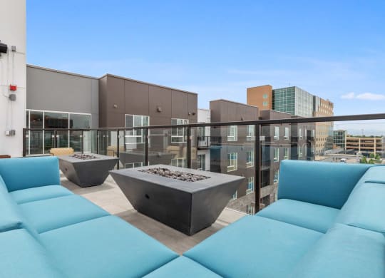 a rooftop patio with blue couches and a fire pit
