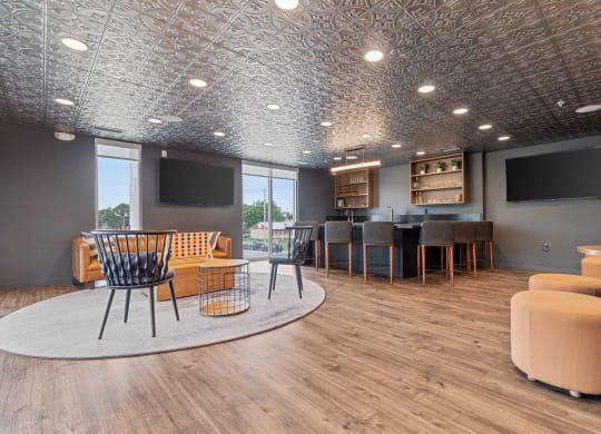 a lounge area with chairs and tables and televisions
