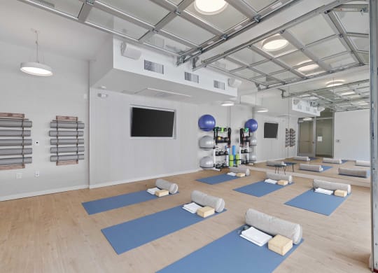 a spacious yoga room with yoga mats and a tv