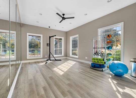a workout room with mirrors and a ceiling fan