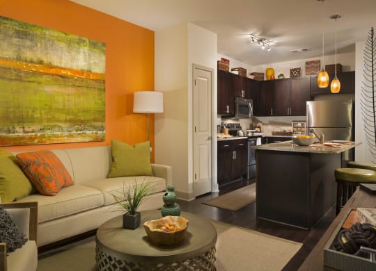a living room with an orange accent wall and a kitchen