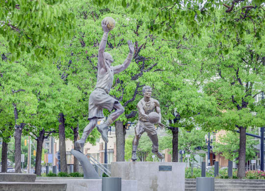 a statue of a man jumping to catch a basketball in a park