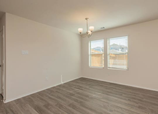 a bedroom with hardwood floors and two windows at The Village at Granger Pines, Conroe