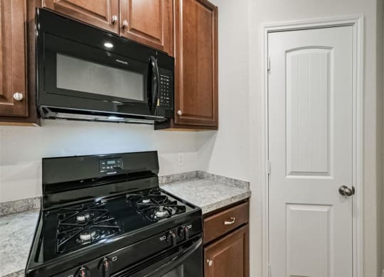 a kitchen with a stove and a microwave at The Village at Granger Pines, Conroe