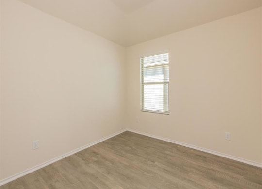 an empty room with a window and a wooden floor at The Village at Granger Pines, Texas