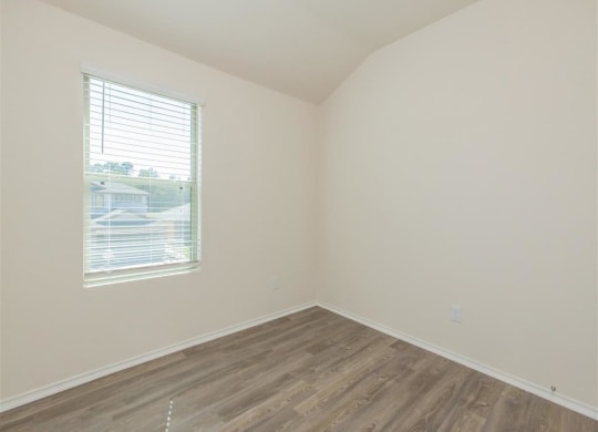 an empty room with a window and wooden floors at The Village at Granger Pines, Conroe Texas