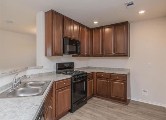 a kitchen with a stove top oven next to a sink at The Village at Granger Pines, Texas