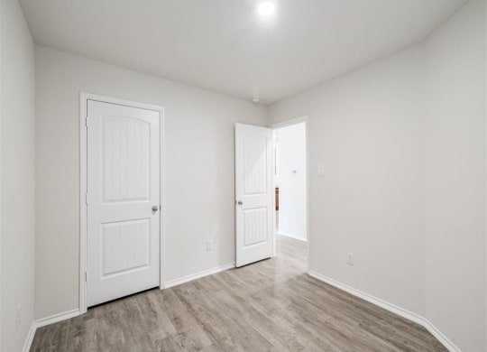 a bedroom with two doors and a hardwood floor at The Village at Granger Pines, Conroe, 77302