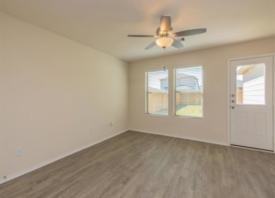 an empty room with a ceiling fan and two windows at The Village at Granger Pines, Texas, 77302