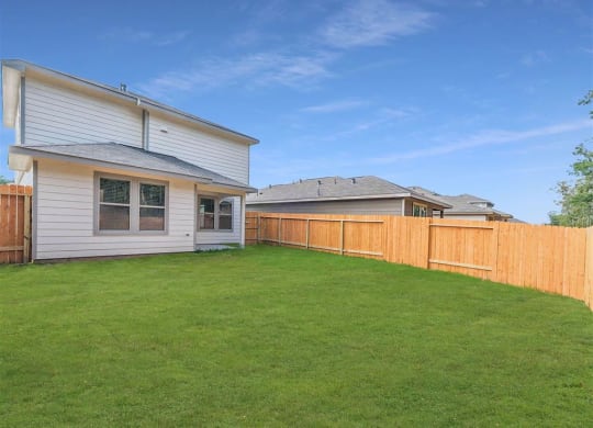 a backyard with a house and a wooden fence at The Village at Granger Pines, Conroe, 77302