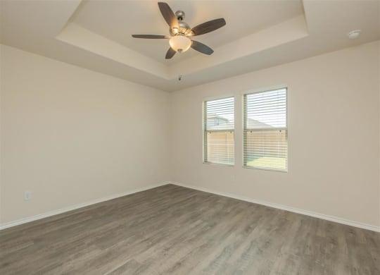 a bedroom with a ceiling fan and two windows at The Village at Granger Pines, Texas, 77302