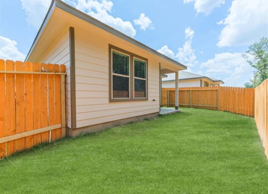 a house with a yard and a wooden fence  at The Village at Granger Pines, Conroe, TX 77302