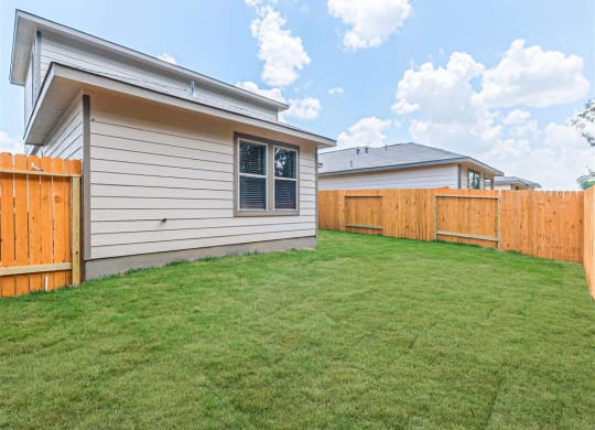 a backyard with a fence and a house at The Village at Granger Pines, Conroe, 77302