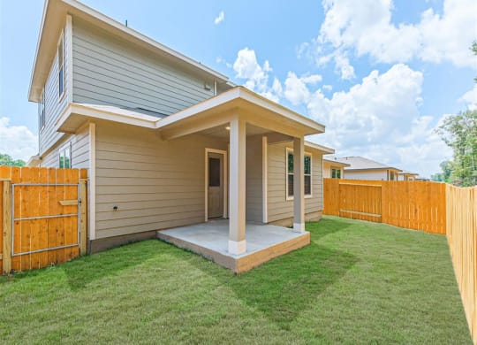 a home with a wooden fence and a green lawn at The Village at Granger Pines, Texas, 77302