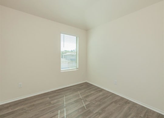 an empty room with a window and a wooden floor at The Village at Granger Pines, Conroe, 77302