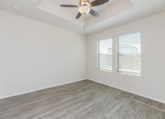 a bedroom with a ceiling fan and two windows at The Village at Granger Pines, Conroe