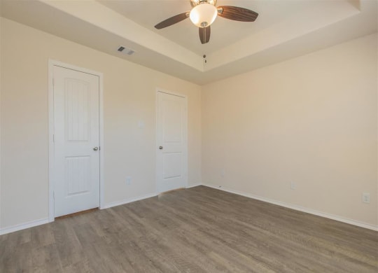a bedroom with white walls and a ceiling fan at The Village at Granger Pines, Texas