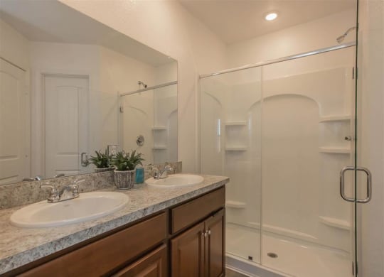 a bathroom with two sinks and a shower at The Village at Granger Pines, Conroe
