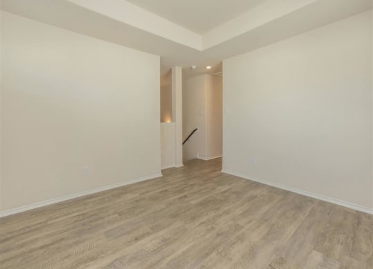 a living room with white walls and a wooden floor at The Village at Granger Pines, Texas