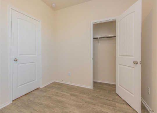 a bedroom with two doors and a closet at The Village at Granger Pines, Texas, 77302