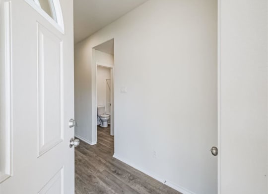 a bedroom with a white door and a bathroom in the background at The Village at Granger Pines, Conroe, 77302