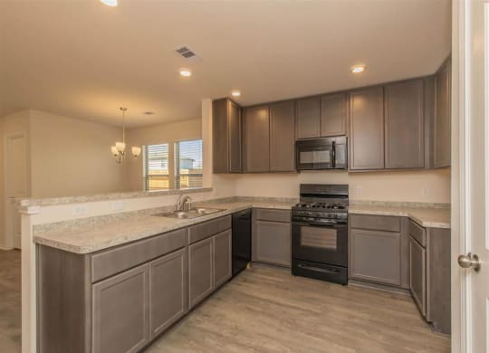 a kitchen with a stove top oven next to a sink at The Village at Granger Pines, Conroe, TX