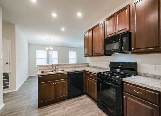 a kitchen with a stove top oven next to a sink at The Village at Granger Pines, Conroe, TX