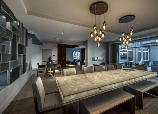 Resident lounge at RE150 Apartments in Medford, MA, featuring a long table surrounded by chairs and modern decor.
