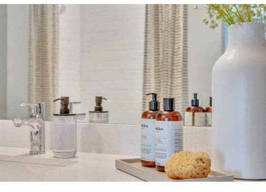 a white vase sitting on a bathroom counter next to a mirror