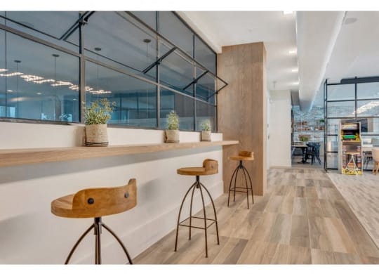 a bar with three stools in a room with large windows