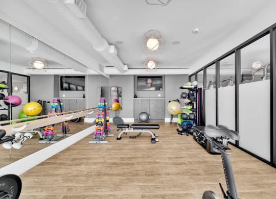 a workout room with a wood floor and mirrored walls and exercise equipment