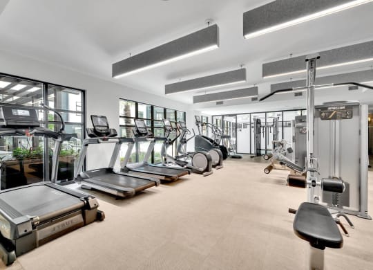 a gym with cardio equipment and windows in a building