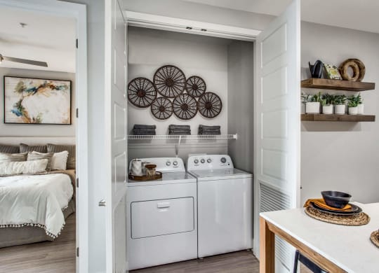 a white washer and dryer in a laundry room with a bed