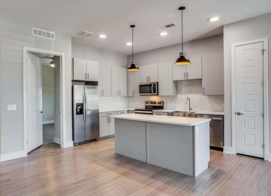 an empty kitchen with white cabinets and a stainless steel refrigerator