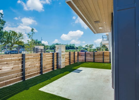 a yard with a fence and grass and a view of a parking lot
