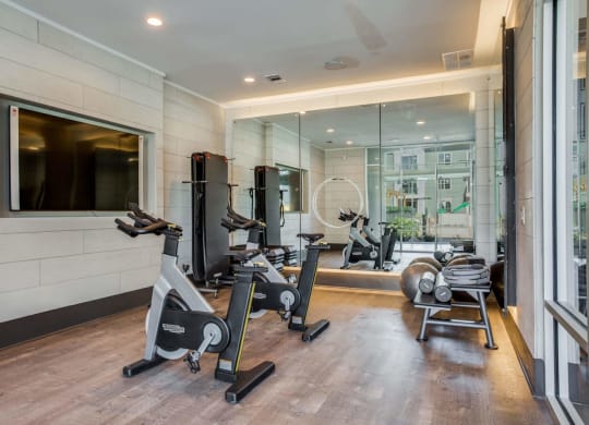 a gym with treadmills and exercise equipment in a room with a large window