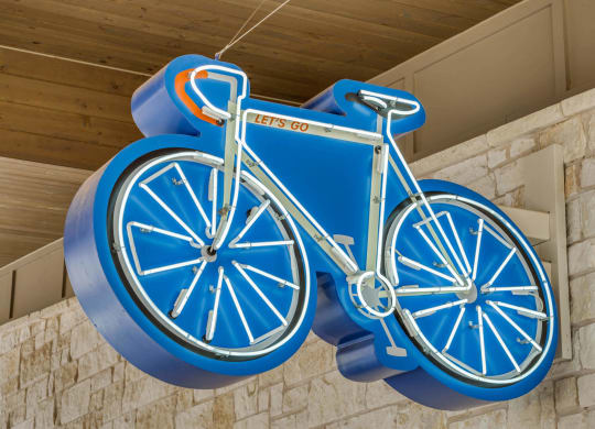 a blue bicycle sign hanging from the side of a building
